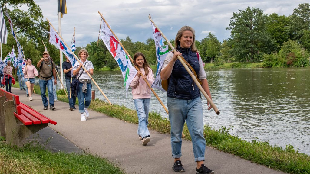 People with flags marching along a river