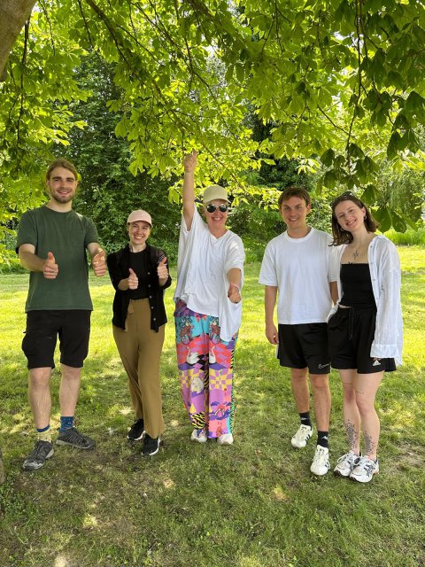Five people standing under a large tree. 
