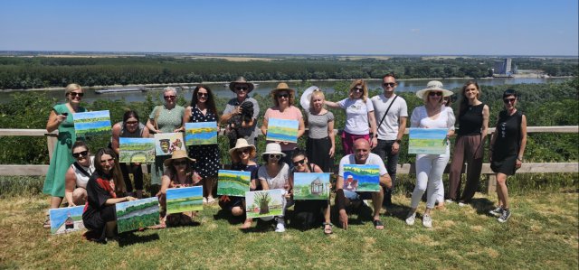 Group of people stands together holding up Danube artwork.