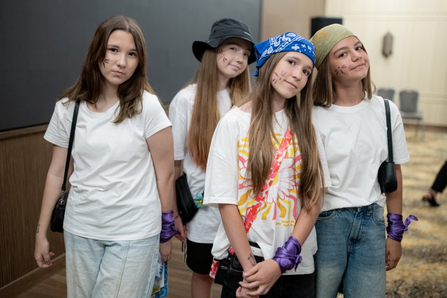 Four girls wearing casual white shirts pose together and smile during an indoor Danube Day event.