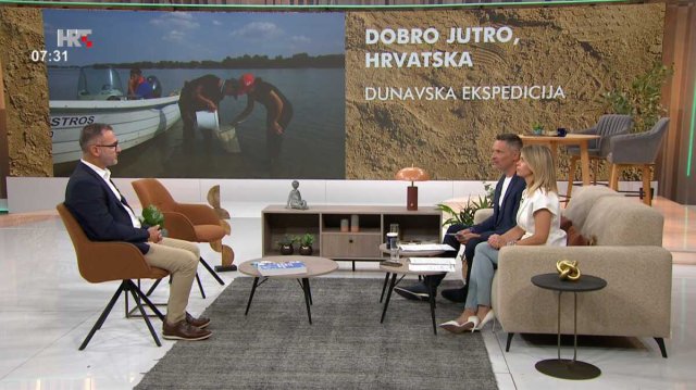 Three people sit at a talk show together. 