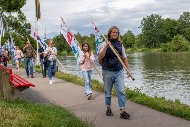 People with flags marching along a river