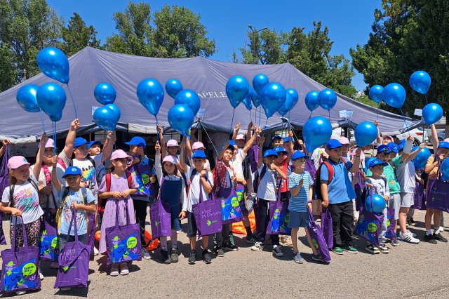 Children holding blue balloons and posing for a photo under a tent 