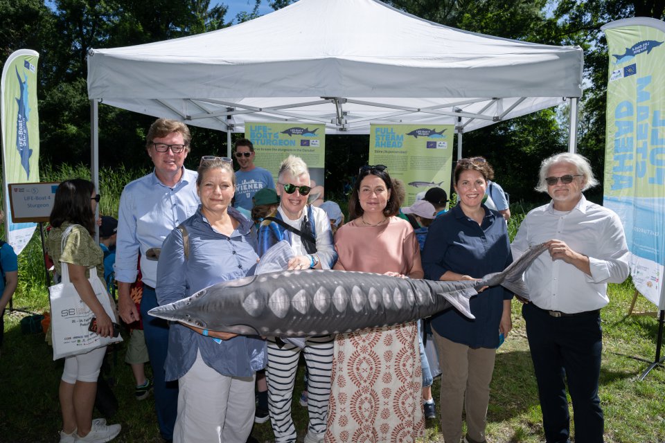 Adults posing with toy sturgeon 