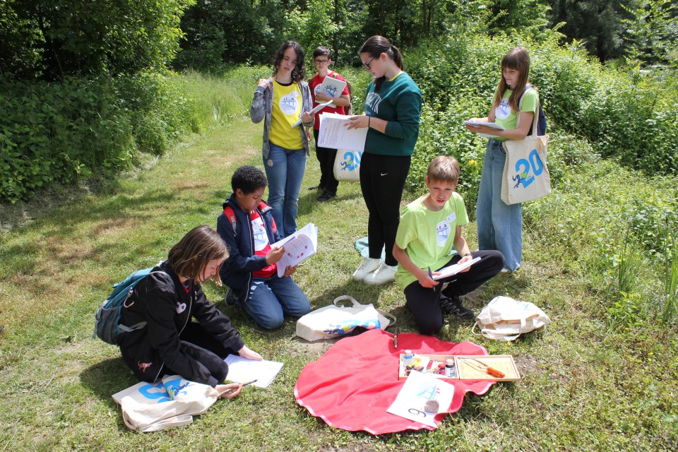 Several children outside writing on paper with pencils. 