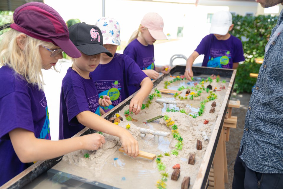 Children playing with sand in purple tshirts
